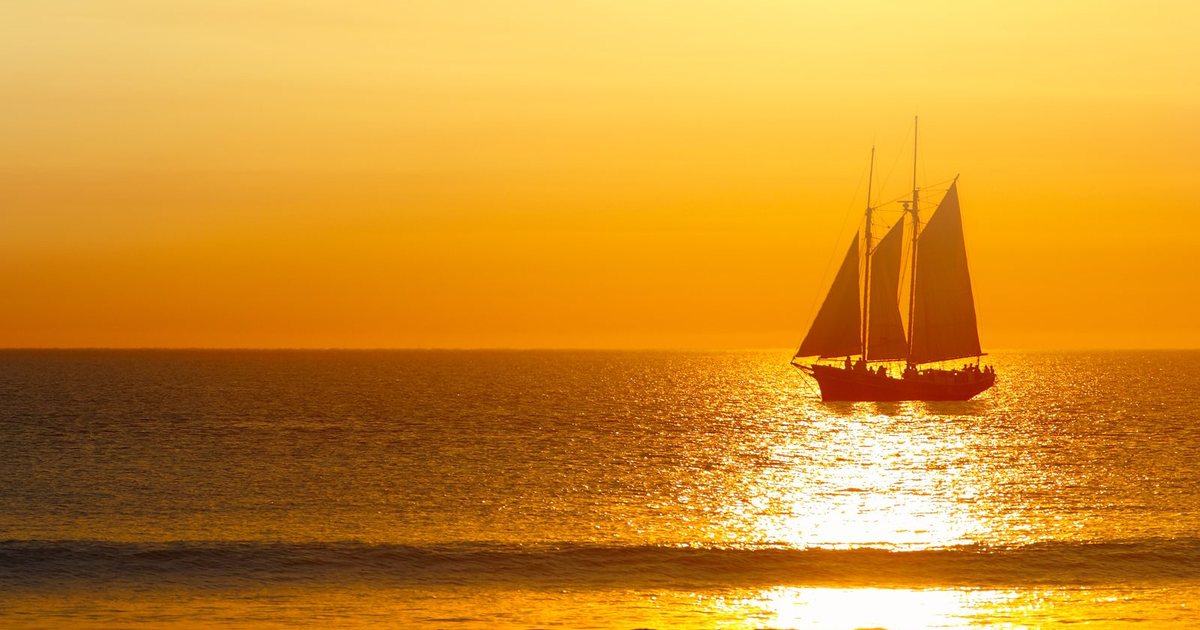 A schooner under sail at sunset