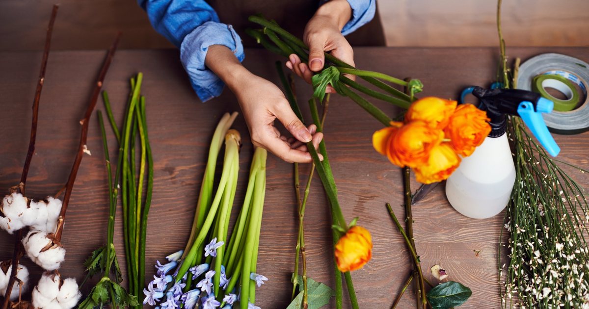 Hands arranging flowers on a wooden table