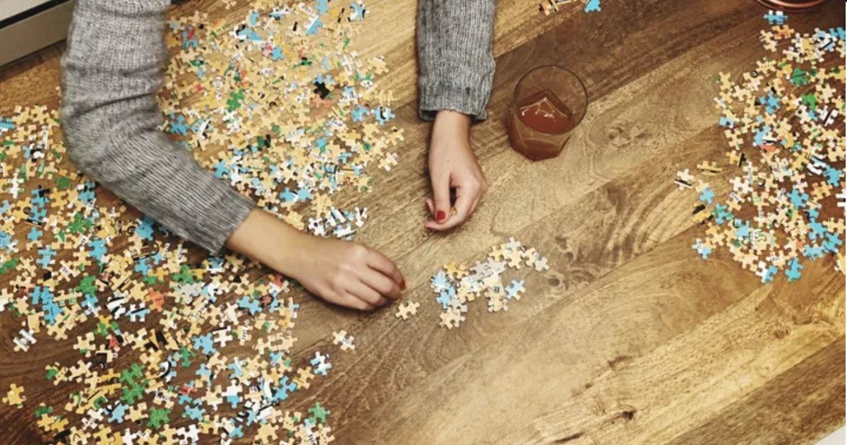 Hands sorting jigsaw puzzle pieces on a table