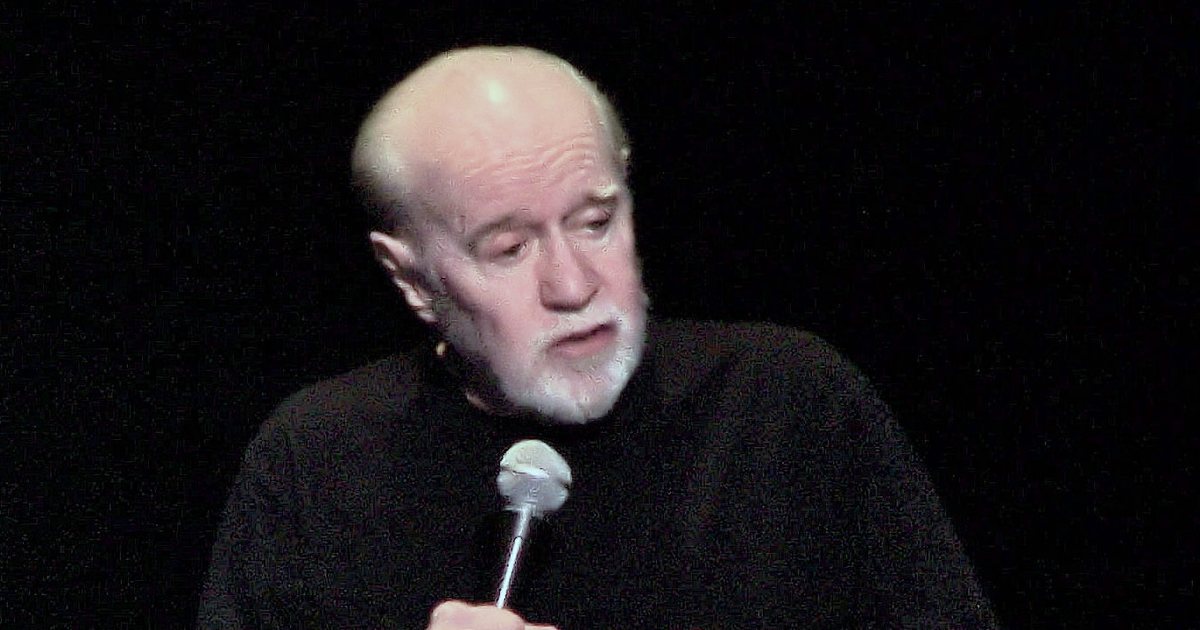 George Carlin on stage with a microphone